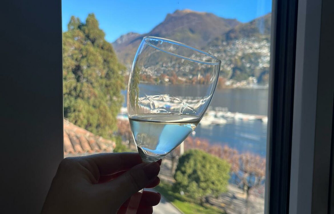 Bicchiere vino bianco con sfondo lago Ceresio di Lugano