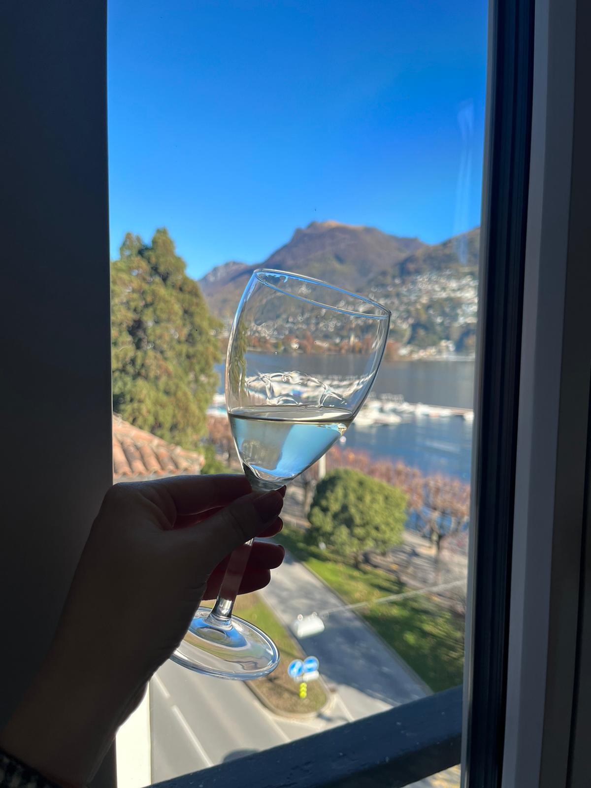 Bicchiere vino bianco con sfondo lago Ceresio di Lugano